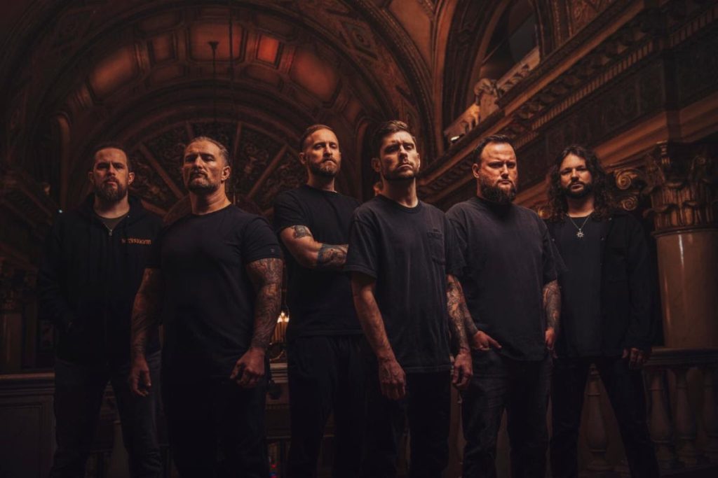Whitechapel band photo 2025 lineup standing in dimly lit ornate hall promoting Hymns In Dissonance and Rituals Of Hate US Tour