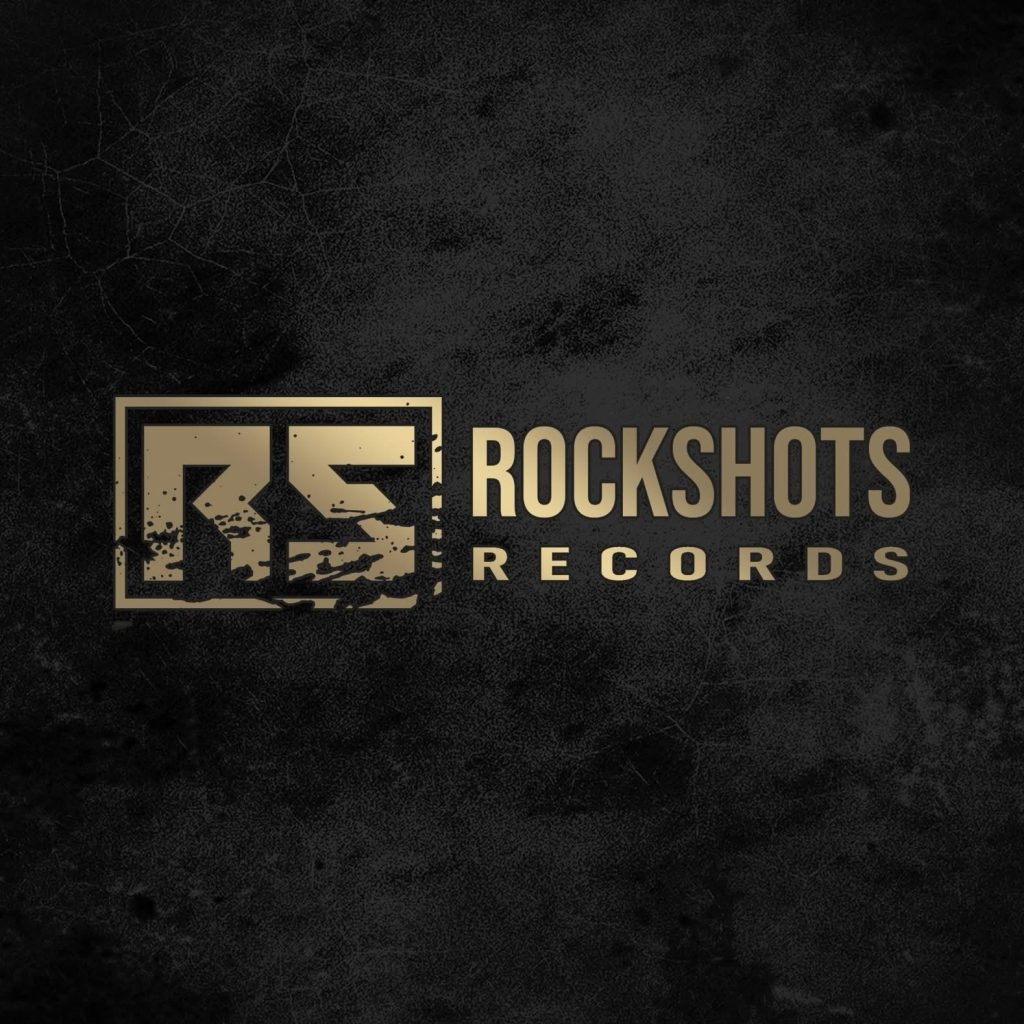 Rockshots Records logo in bold gold letters on a textured black background, featuring the initials “RS” in a distressed square frame.