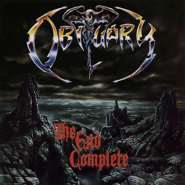 Album cover of Obituary’s “The End Complete.” The band’s jagged logo appears at the top with a demonic figure forming part of the lettering. Below, the album title is written in blood-red gothic font. The background depicts a bleak, rocky wasteland under a stormy sky, evoking a dark and apocalyptic atmosphere.