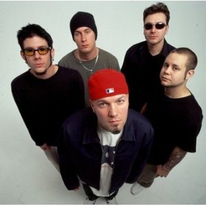 “Band photo of Limp Bizkit in the early 2000s — Fred Durst in red cap, with other members dressed in black, posed against white background.”
