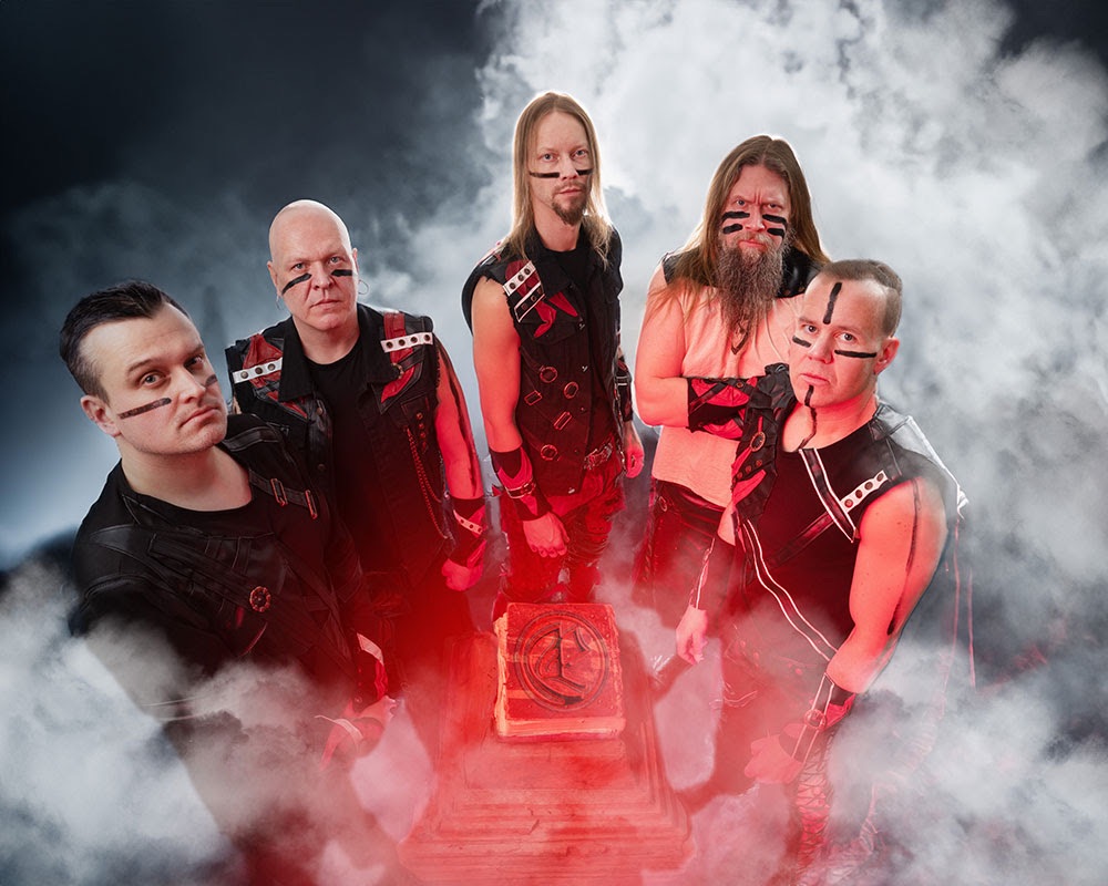Ensiferum band photo 2025 – Finnish folk metal band members in warrior-inspired black and red outfits with warpaint, surrounded by smoke.