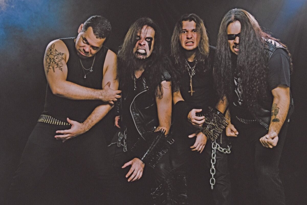 Black metal band Grave Desecrator posing in a dark studio, wearing leather, spikes, corpse paint, and aggressive expressions.