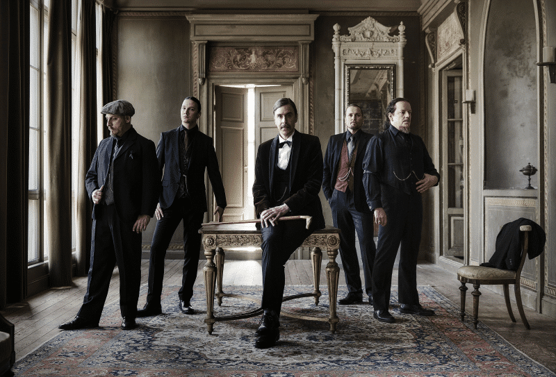 Opeth band members posing in vintage formal attire for an official promotional photo led by Mikael Åkerfeldt.
