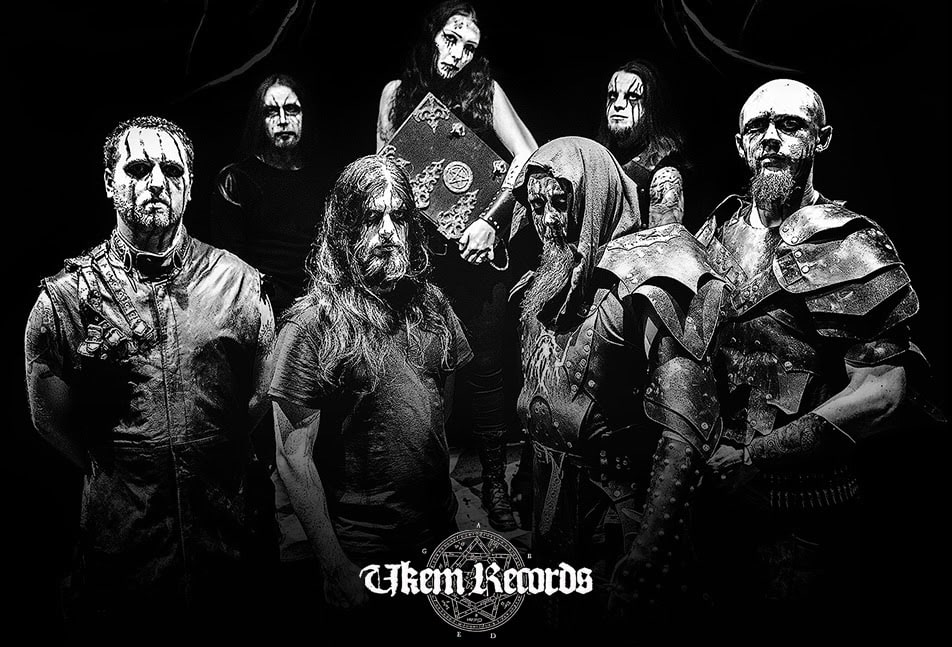 “Agrona band photo. Seven members in full black metal warpaint and dark armor, standing together in a dramatic black and-white promo shot.”