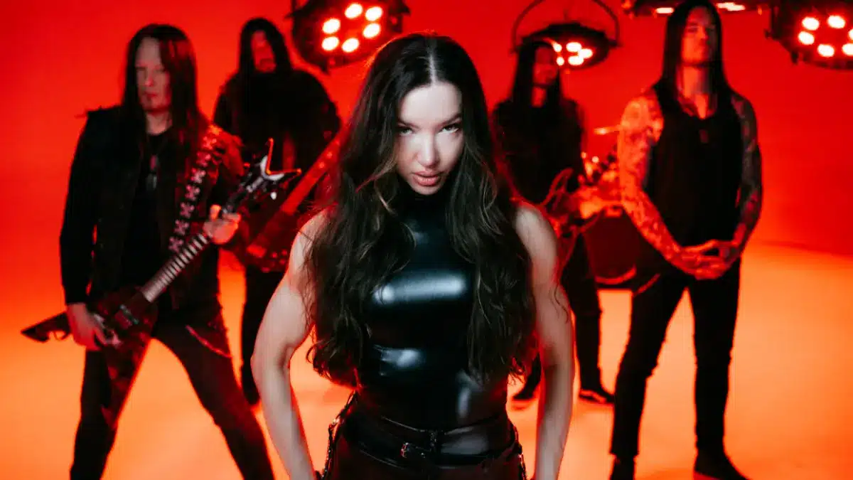 Arch Enemy performing under intense red lighting with vocalist Lauren Hart standing front and center during the band’s 2026 era.