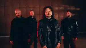 Progressive metal band Haken standing under moody red and dark cinematic lighting during the band’s 2026 era.