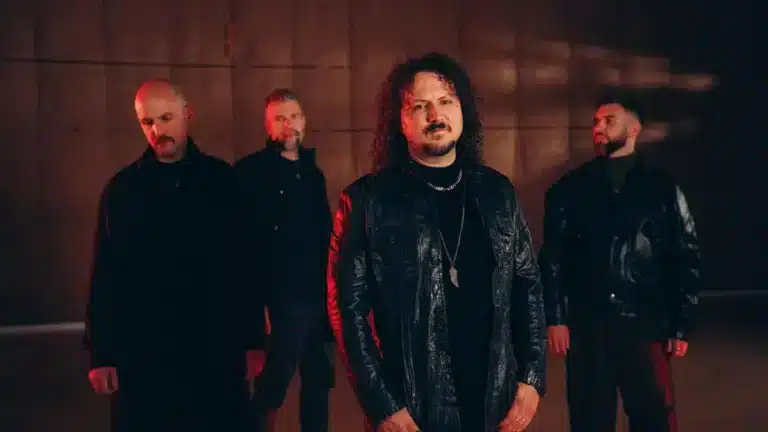 Progressive metal band Haken standing under moody red and dark cinematic lighting during the band’s 2026 era.