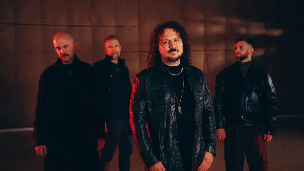 Progressive metal band Haken standing under moody red and dark cinematic lighting during the band’s 2026 era.