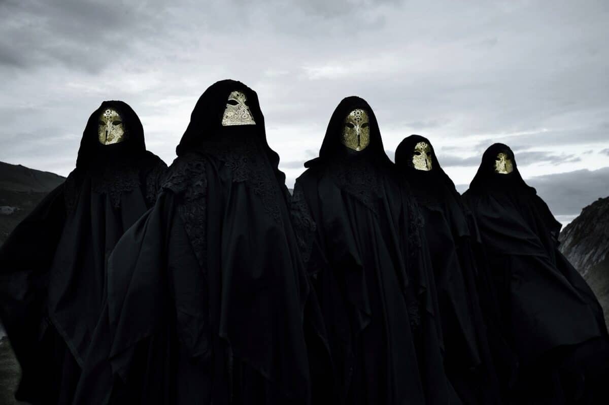 Avant-garde black metal band Schammasch wearing ritual cloaks and masks in a dark ceremonial landscape for World Metal Weekly
