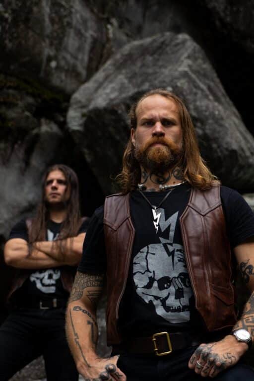 Swiss blackened death metal duo Bölzer standing outdoors in rugged natural scenery for World Metal Weekly Switzerland