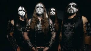 Nargaroth promotional band photo featuring four members in black metal corpse paint, leather battle vests, spikes, and black clothing against a dark studio background.