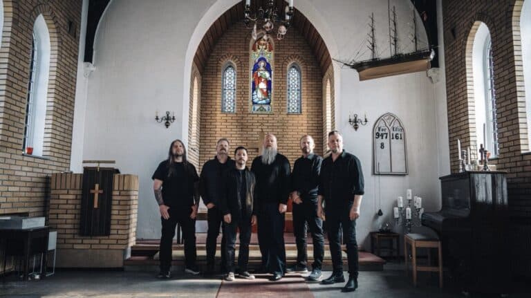 Green Carnation pose inside a church sanctuary with stained-glass windows while promoting their 2026 album A Dark Poem, Part III: The Messiah Complex.