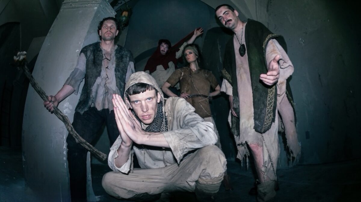 Members of Netherwilds pose in medieval-inspired costumes inside a stone building, reflecting the band's fantasy folk aesthetic.