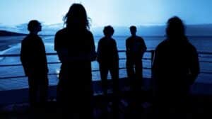 The Larches promotional band photo featuring the five members standing on a seaside pier at dusk.