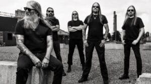 Amon Amarth band promotional photo featuring the five members in an industrial outdoor setting