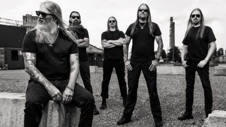 Amon Amarth band promotional photo featuring the five members in an industrial outdoor setting