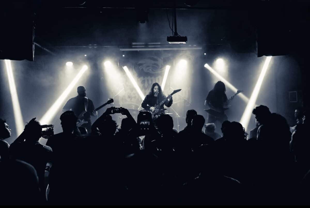Demonic Resurrection performing live onstage under bright lights before a packed crowd