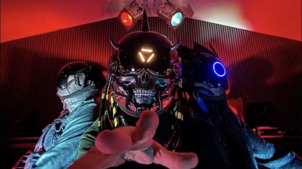 iAtlas band photo featuring three members in futuristic helmets under red stage lighting