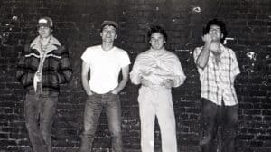 Descendents Milo Goes to Comics announcement featuring a vintage black-and-white photograph of the punk rock band standing against a brick wall.