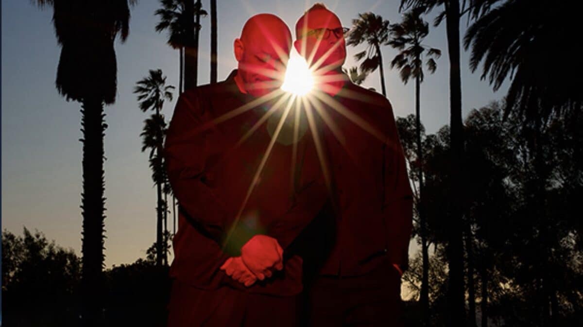 Burn Eternal Howard Jones Adam Dutkiewicz official promotional photo featuring the two musicians standing back-to-back beneath a dramatic sunburst.