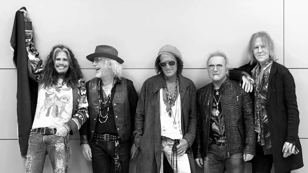 Aerosmith Joey Kramer Reunion featuring all five classic band members, Steven Tyler, Joe Perry, Joey Kramer, Tom Hamilton and Brad Whitford, posing together in a black-and-white photograph.