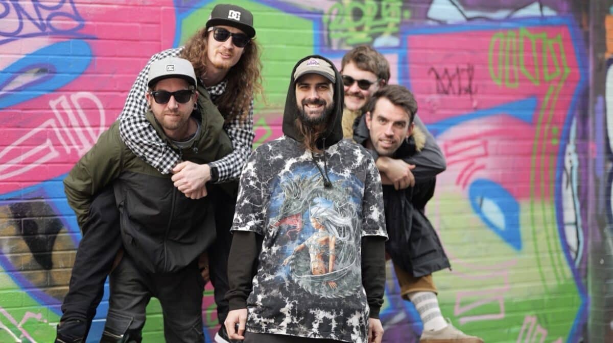 Look What Happened Weak Minds for the Weekend review – Brighton pop-punk band posing together in front of a colorful graffiti wall.